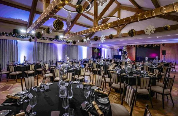 A large hall with a beam ceiling, many tables and chairs, decorated for Christmas