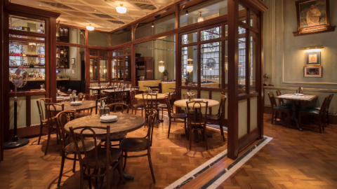 Table and chairs inside a wood and glass panelled restaurant with parquet flooring