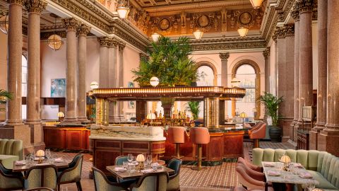 The opulent canopied bar and dining room at Gleaneagles townhouse with marble pillars, friezes and a large palm. Decoration and furnishings are mostly pistachio green and pastel pink
