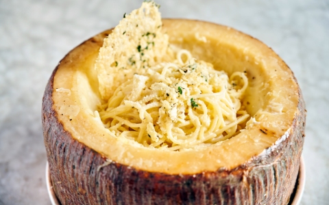 A hollowed pecorino wheel containing spaghetti and cheese