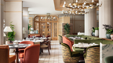 Tables and chairs set yp with tea cups and hanging lights above in a well lit and bright hotel lobby
