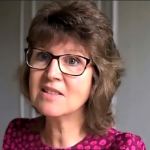 A colour portrait of Catherine Condie on a grey background. Catherine is a white woman with dark hair and glasses, who wears a pink patterned top.