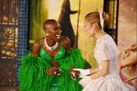 Cynthia Erivo laughing while Ariana Grande hold one of her hands