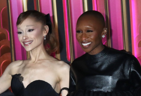 Ariana Grande on the left and Cynthia Erivo on the right both smiling directly to the camera