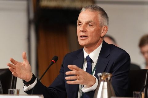 Tim Davie sat with his arms slightly raised above a desk. He is wearing a dark suit and tie.