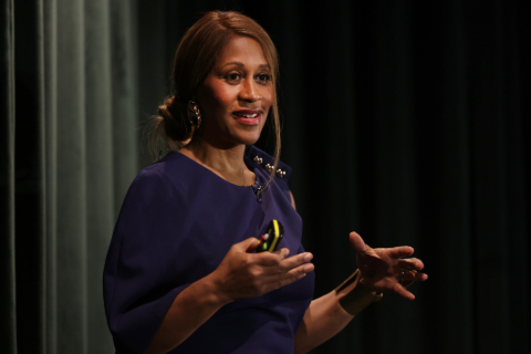 Karen Blackett on stage in front of a dark green curtain.
