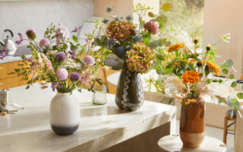 An assortment of colourful flowers in vases on a contemporary kitchen worktop