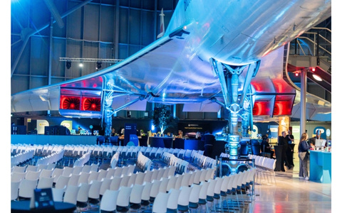 white chairs is a lecture set up underneath a Concorde plane